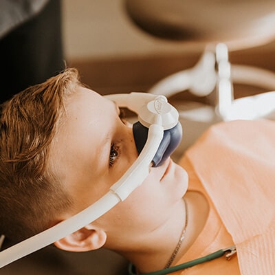 A young male patient wearing a nasal hood so he can receive children's dentistry