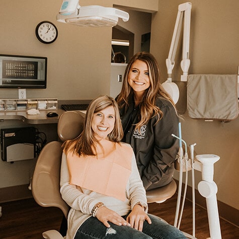 One of our dental assistants sitting next to a female patient while they both smile