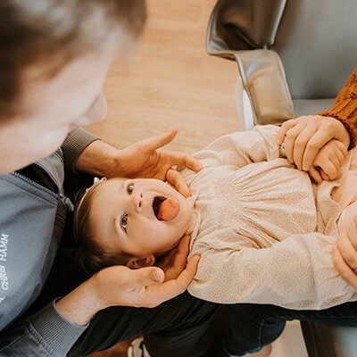 A baby getting children's dentistry and sticking its tongue out