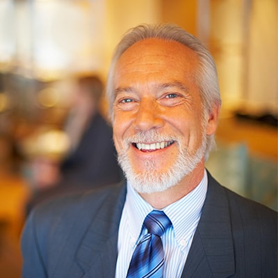 An older man smiling in a suit